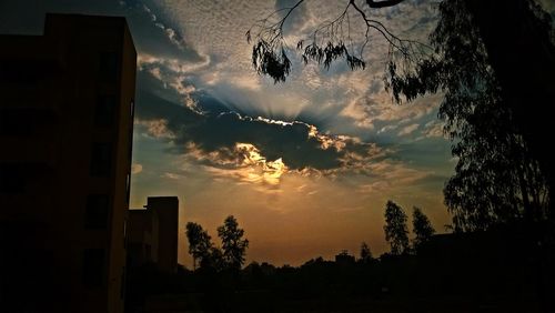 Low angle view of silhouette trees against dramatic sky