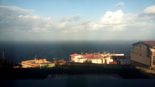 Houses in town by sea against sky