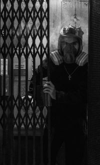 Man holding umbrella while standing by fence