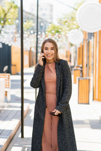 Young happy woman is walking around the city, talking on a mobile phone.