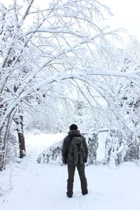 Rear view of man walking on snow covered landscape