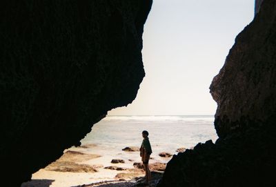 People standing on rock by sea against sky