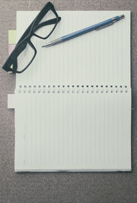 Directly above shot of open spiral notebook with eyeglasses and pen on table