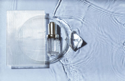 Cosmetic spa medical skincare, glass serum bottle in petri dish with collagen on blue water back