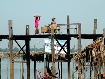 Wooden post on pier by sea against clear sky