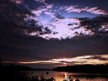 Scenic view of lake against dramatic sky during sunset