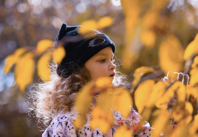 Close-up of young woman with autumn leaves