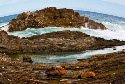 Rock formation on beach against sky