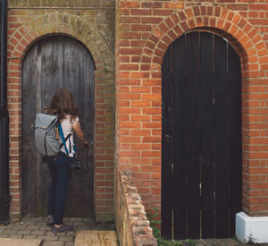 Woman standing against brick wall of building