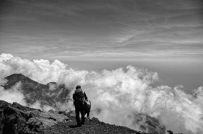 Rear view of man standing on mountain against sky