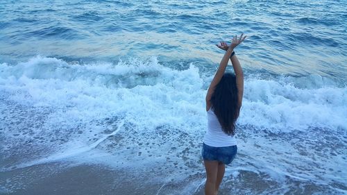 High angle view of woman with arms raised standing in sea