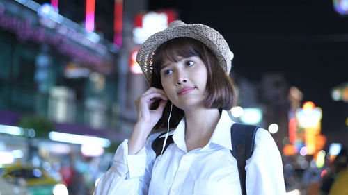 Portrait of young woman using mobile phone in city at night