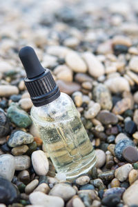 Cosmetic serum in a glass bottle with a pipette on stones