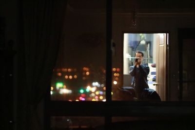 Young woman using mobile phone while sitting in kitchen