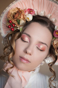 Close-up of beautiful young woman wearing flowers and hat