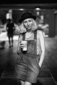 Portrait of young woman having coffee while standing outdoors