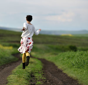 Rear view of woman running on field