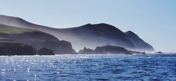 Scenic view of sea and mountains against clear sky