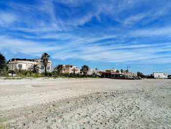 Houses on beach by buildings against blue sky