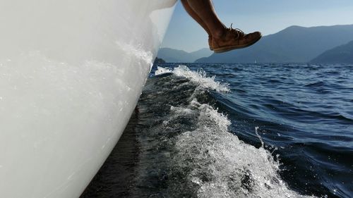 Low section of man in boat over sea against sky