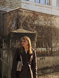 Young woman wearing hat standing against bare tree