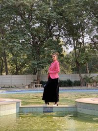 Woman standing by swimming pool against lake