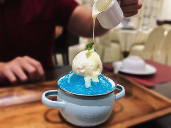 Midsection of person pouring liquid over desert on table at restaurant