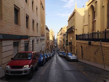 Vehicles on road along buildings in city