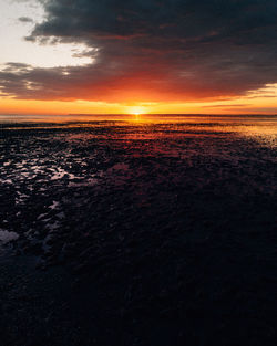 Scenic view of sea against dramatic sky during sunset