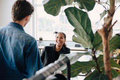 Cheerful businesswoman talking to male colleague at office