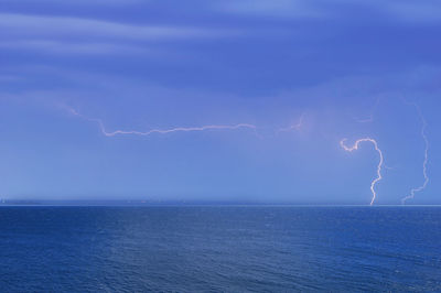 Beautiful landscape with lightning over the calm sea at sunset