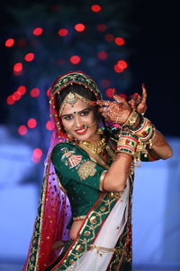 Portrait of young woman in illuminated traditional clothing