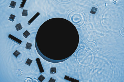 Abstract black geometric figures composition on transparent blue clear water
