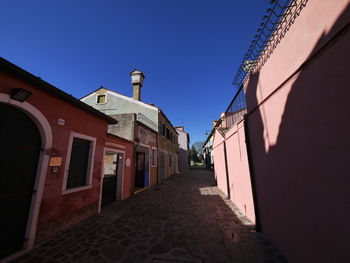 Street amidst buildings against clear blue sky