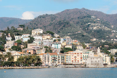 Aerial view of townscape by sea against sky