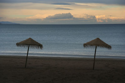 Lifeguard hut on beach against sky during sunset