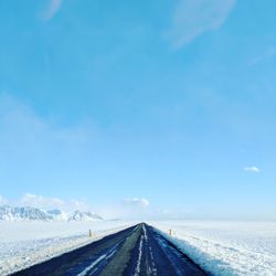 Road amidst landscape against blue sky