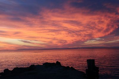 Scenic view of sea against cloudy sky at sunset