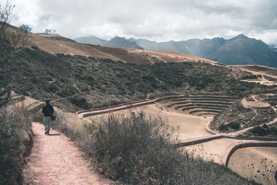 Rear view of woman walking on pathway on mountain