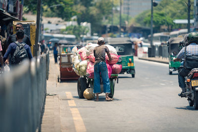 Rear view of people walking on road in city