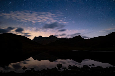 Scenic view of lake and mountains against sky at night