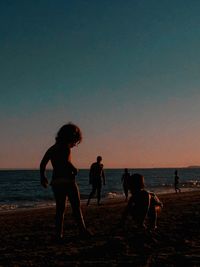 People on beach against sky during sunset