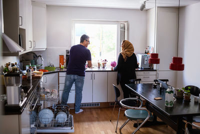 Rear view of couple standing in kitchen