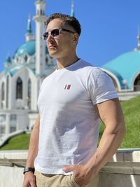 Young man wearing sunglasses standing against built structure