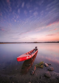 Boat on beach against sky during sunset