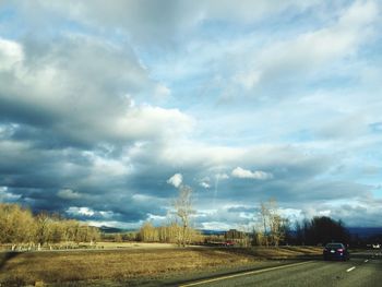 Road passing through landscape against cloudy sky