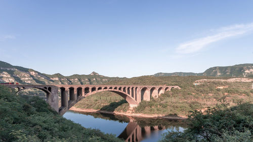 Arch bridge over river against sky