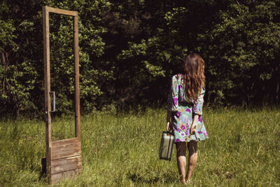 Rear view of woman with umbrella on field
