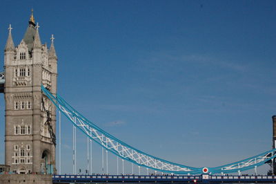 Low angle view of suspension bridge against blue sky