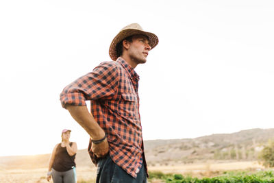 Side view of young man standing against clear sky